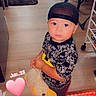 baby, black_cap, child, date_text, duck_toy, furniture, graphic_shirt, home, hugging, indoors, living_room, looking_at_camera, plush_toy, portrait, red_led_lights, sandals, standing, toddler, wide_eyed, wood_floor