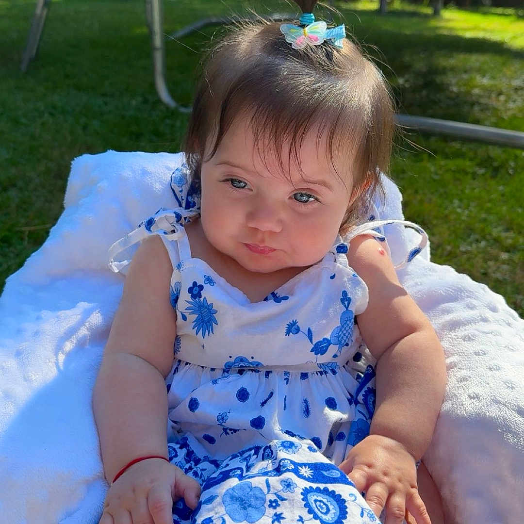 Sofia a rejoint le concours — aidez-le/la à gagner de superbes lots ! baby, blanket, blue_and_white, child, cute, dress, floral_pattern, garden, girl, grass, hair_clip, happy, infant, nature, outdoor, person, pony_tail, sitting, summer, sunlight
