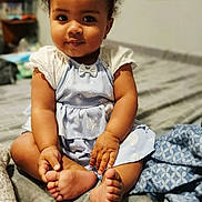 Olivia joined the competition — help win amazing prizes! baby, child, curly_hair, blue_dress, bow, barefoot, bed, blanket, cozy, indoors, portrait, cute, smile, skin, hands, feet, furniture, home, person, infant