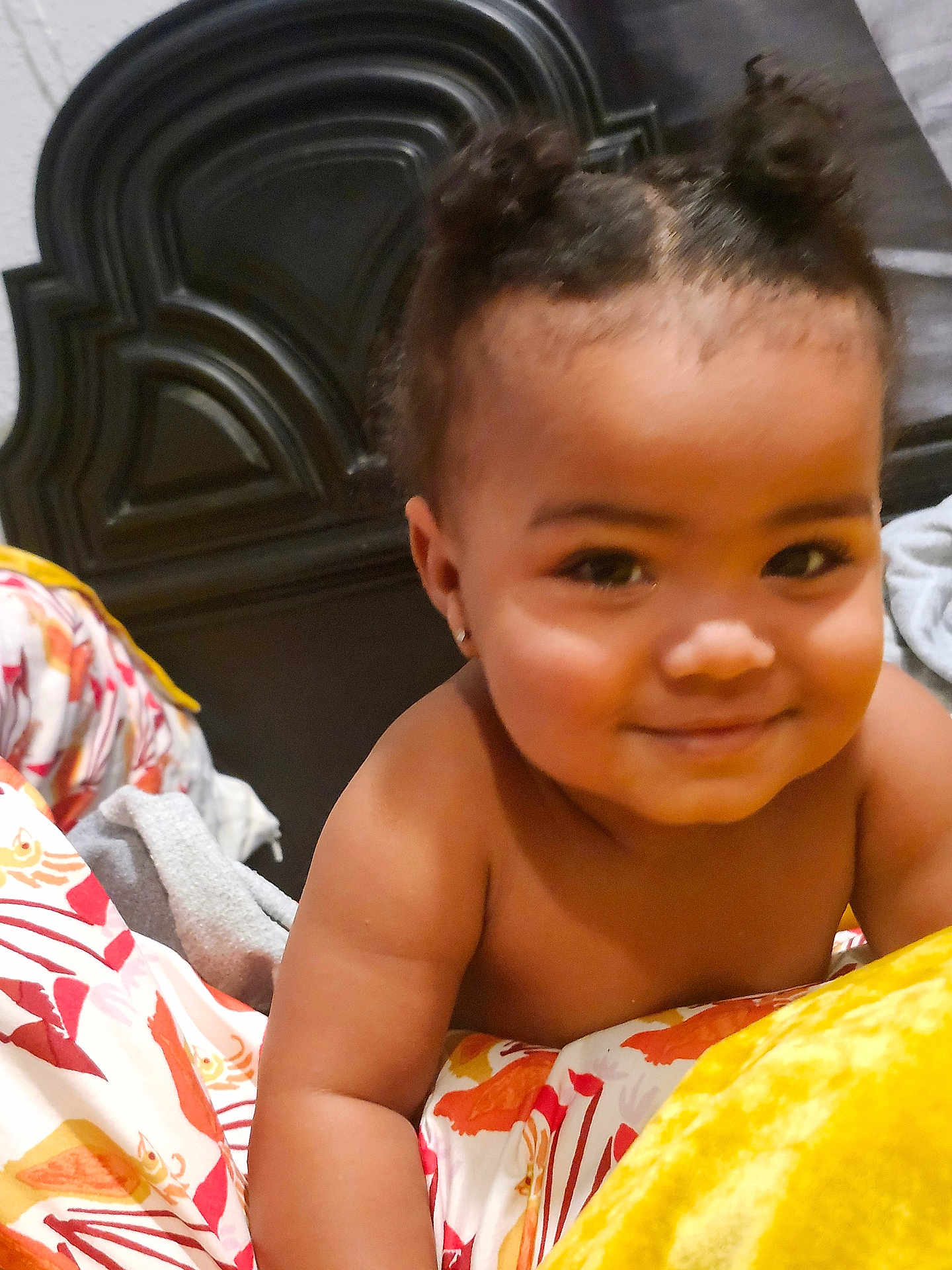 Olivia joined the competition — help win amazing prizes! baby, child, smiling, hair_buns, bedroom, bedding, patterned_bedspread, face, skin, earrings, happy, infant, lying_down, indoors, headboard, comfort, cute, portrait, young_child, expression