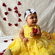 Brillith joined the competition — help win amazing prizes! baby, blanket, celebration, child, cute, decor, fabric_flowers, golden_shoes, happy, headband, heart_shape, indoors, portrait, red_rose, rose_petals, sitting, smiling, white_bow, yellow_dress, young_child