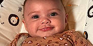 Georgia is registered to the contest to win money with this photo: baby, smiling, child, infant, face, eyes, hand, leg, clothing, pattern, leopard_print, seat, baby_seat, animal_pattern, cute, happy, indoor, portrait, skin, young