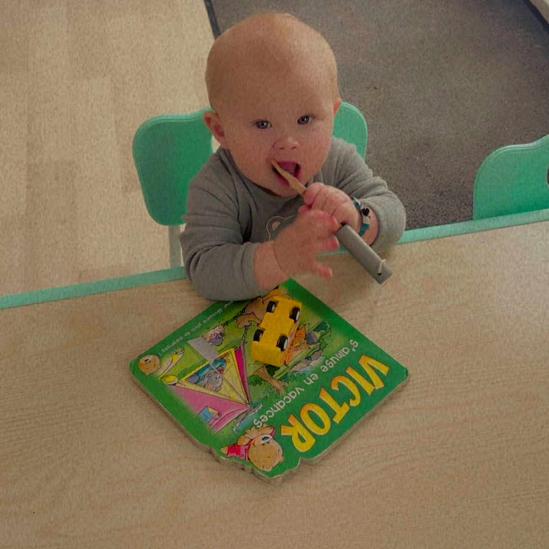 Aliciano participe au concours pour gagner de l'argent avec cette photo : baby, book, chair, child, curious, floor, footwear, furniture, home, indoor, learning, mat, person, play, reading_material, shoes, table, toy_car, wooden_stick, young_child