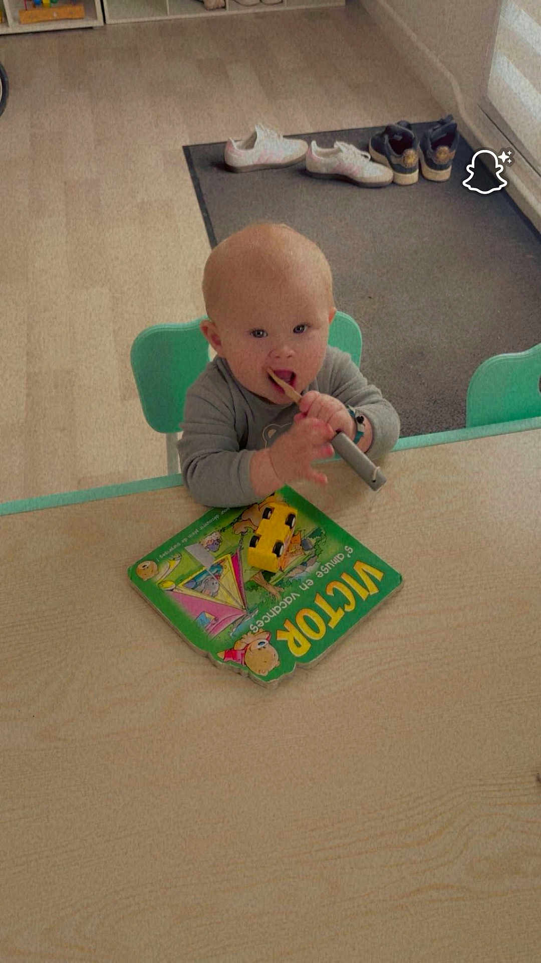 Aliciano participe au concours pour gagner de l'argent avec cette photo : baby, child, table, book, toy_car, wooden_stick, shoes, floor, mat, chair, indoor, play, curious, young_child, person, reading_material, footwear, furniture, home, learning