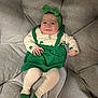 Isabelle is registered to the contest to win money with this photo: baby, infant, smiling, headband, bow, green_outfit, clover_pattern, tights, socks, couch, cushion, seated, portrait, happy, cute, hand, legs, face, eyes, fabric