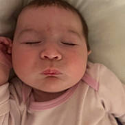 Isabelle is registered to the contest to win money with this photo: baby, infant, sleeping, closed_eyes, face, onesie, pink, pillow, bed, mouth, cheeks, newborn, cozy, indoor, portrait, peaceful, lips, hand, clothing, head