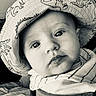 baby, infant, child, portrait, face, eyes, wide_eyed, looking_at_camera, hat, dinosaur_pattern, blanket, striped_blanket, seated, close_up, black_and_white, indoor, cozy, soft_lighting, photography, calm