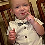 Cooper is registered to the contest to win money with this photo: toddler, child, boy, white_shirt, bow_tie, button_up, wooden_chair, indoor, curious, posing, short_hair, smiling, cute, person, seated, furniture, skin, face, hand, portrait