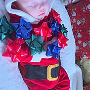 Oakley joined the competition — help win amazing prizes! baby, sleeping, red_clothing, santa_outfit, holiday_bows, gift_bows, christmas, festive, wrapped_presents, blanket, face, infant, cute, holiday_decor, christmas_theme, toddler, cozy, indoors, child, holiday_season