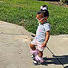 Brielle is registered to the contest to win money with this photo: toddler, child, outdoor, sidewalk, grass, sunglasses, pacifier, hair_bow, shorts, tshirt, shoes, shadow, sunny, walking, cute, fashion, accessories, young_child, summer, playful