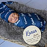 newborn, baby, sleeping, swaddle, hat, basket, fluffy_blanket, birth_announcement, wooden_plaque, personalized, blue_clothing, infant, cozy, portrait, indoors, peaceful, cute, baby_boy, soft_texture, newborn_photography