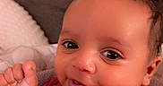Kanan is registered to the contest to win money with this photo: baby, child, infant, smiling, happy, portrait, close_up, indoor, bedroom, bed, blanket, red_clothing, soccer_ball, sportswear, raised_fist, sitting, lying_down, face, eyes, photography