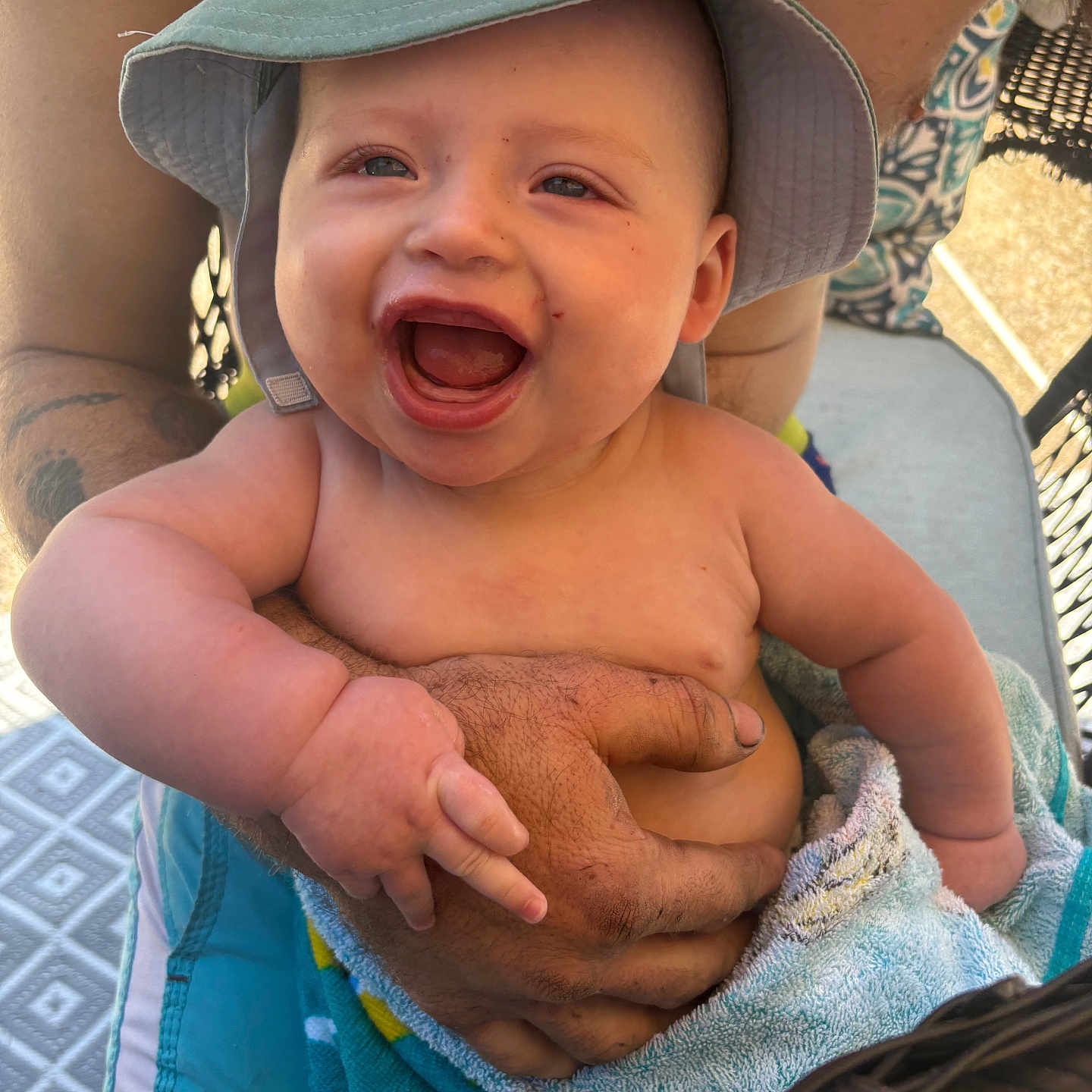 River joined the competition — help win amazing prizes! baby, child, smiling, hat, towel, tattoo, arm, hand, outdoor, sunlight, joy, happy, person, skin, holding, seat, patterned_surface, summer, cute, infant