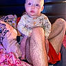 River is registered to the contest to win money with this photo: baby, child, person, leg, bed, blanket, pajamas, onesie, animal_print, hairy_leg, indoors, red_eye, cute, infant, sleepwear, colorful_blanket, resting, cozy, portrait, curious_expression