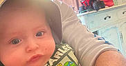 River joined the competition — help win amazing prizes! baby, child, adult, face, hat, shirt, green, toy, lamp, furniture, curtain, indoor, person, arm, hand, cartoon_character, table, box, window, casual