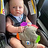 baby, car_seat, child, toy, plush_toy, infant, seatbelt, vehicle, blue_eyes, clothing, hand, foot, warning_label, colorful, fabric, sitting, indoor, cute, person, closeup