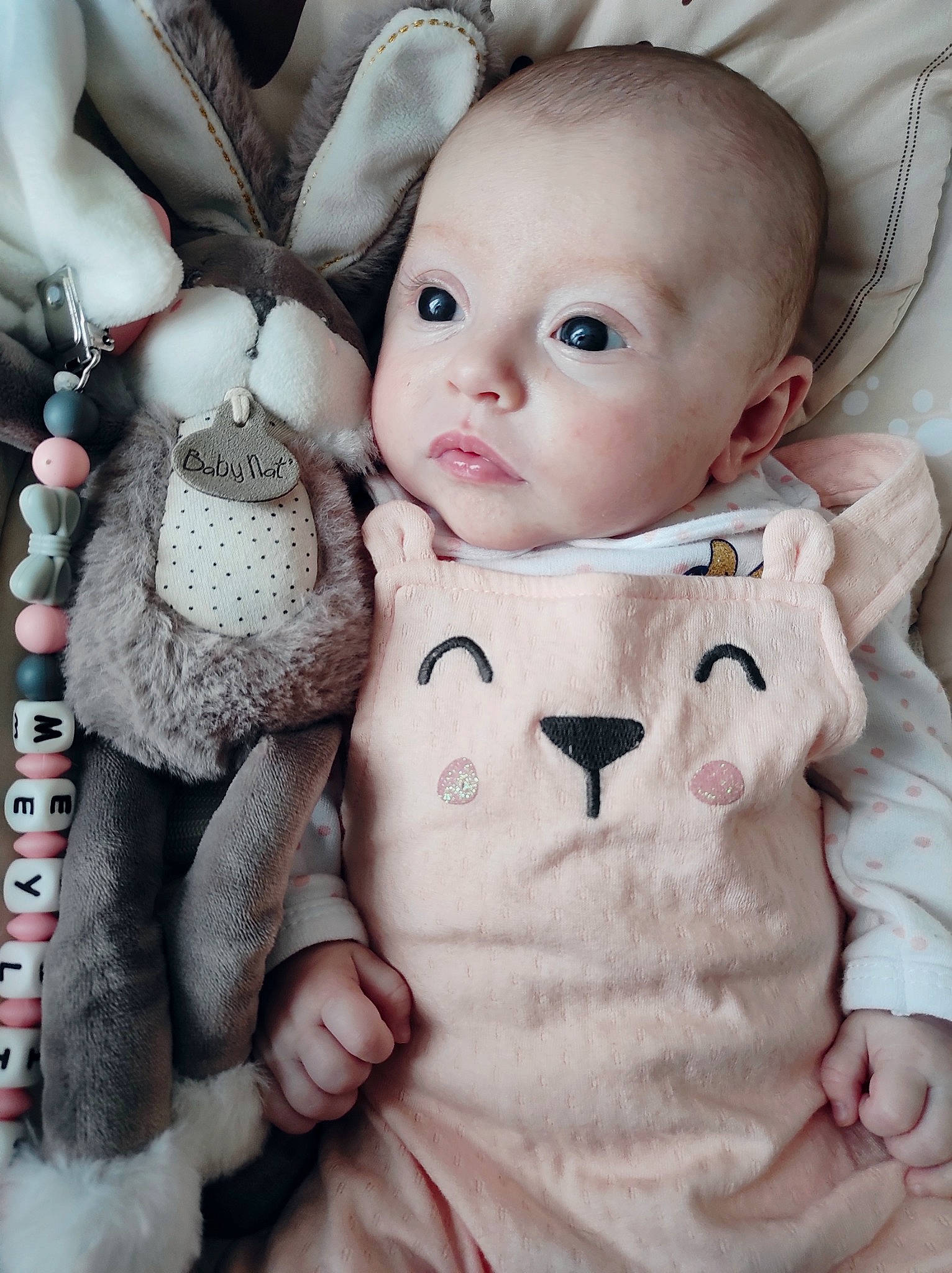 Meyline participe au concours pour gagner de l'argent avec cette photo : baby, baby_toddler_clothing, cheek, child, comfort, eyelash, gesture, iris, linens, lip, nose, outerwear, pattern, person, pink, product, skin, sleeve, textile, toy