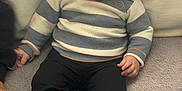 Manil participe au concours pour gagner de l'argent avec cette photo : toddler, child, baby, sitting, striped_sweater, black_pants, white_shoes, bear_socks, soft_surface, couch, curious, holding_hands, indoor, cute, casual_clothing, portrait, young_child, footwear, knitwear, leisure