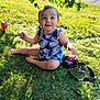 baby, child, grass, outdoor, sunlight, smile, camera, leaf_pattern, blue_clothing, nature, greenery, sitting, happy, face, person, summer, park, toy, cute, eyes