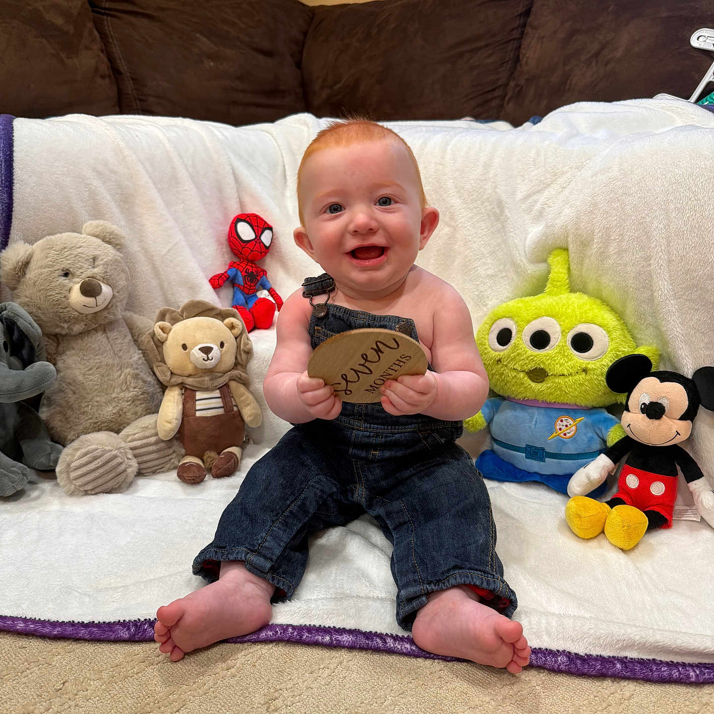 Kyvin joined the competition — help win amazing prizes! alien_toy, baby, blanket, carpet, child, couch, cute, denim_overalls, happy, holding, indoor, infant, lion_plush, mickey_mouse, plush_toys, sitting, smiling, spiderman_toy, teddy_bear, wooden_plaque