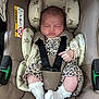 baby, sleeping, car_seat, bunny_pattern, leopard_print, white_socks, infant, child, seatbelt, cute, cozy, resting, clothing, fabric, straps, head_support, newborn, comfort, indoor, safety
