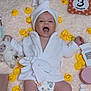 baby, smiling, white_robe, towel_turban, rubber_duck, makeup_brush, makeup, stuffed_toy, blanket, diaper, happy, infant, cosmetics, soft_texture, lying_down, cute, skincare, child, yellow, playful