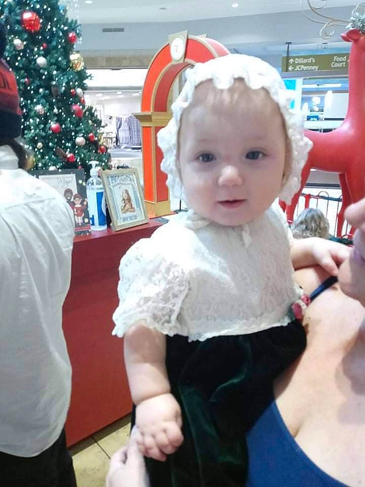 Eris is registered to the contest to win money with this photo: baby, child, christmas, christmas_tree, event, formal_wear, fun, gesture, happy, holiday, holiday_ornament, ornament, party_supply, person, room, santa_claus, standing, t_shirt, toddler, toy