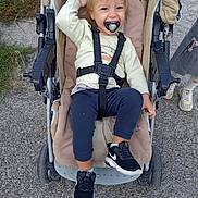 Santiago Loureiro participe au concours pour gagner de l'argent avec cette photo : baby, black_sneakers, blond_hair, casual_clothing, child, footwear, greenery, happiness, outdoor, pacifier, park, pavement, person, playful, safety_straps, smiling, stroller, toddler, toy, transport