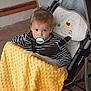 baby, baby_stroller, blanket, child, clothing, curious, face, head, infant, outdoor, pacifier, person, seat_belt, sitting, striped_clothing, stroller, toddler, toy_pattern, winnie_the_pooh, yellow_blanket