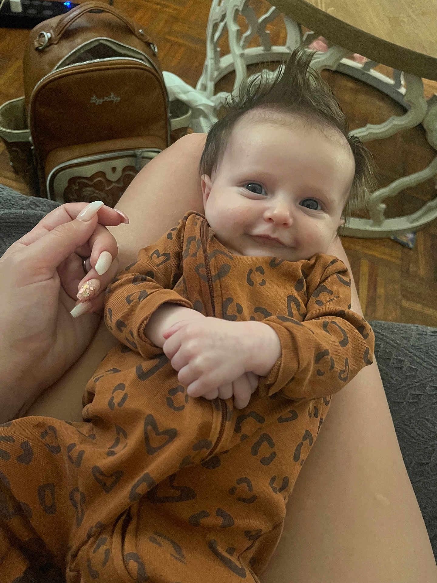 Milania joined the competition — help win amazing prizes! baby, smiling, infant, onesie, brown_clothing, leopard_print, heart_pattern, hand, lap, fingernails, backpack, floor, wooden_floor, furniture, table, indoor, portrait, cute, person, happy