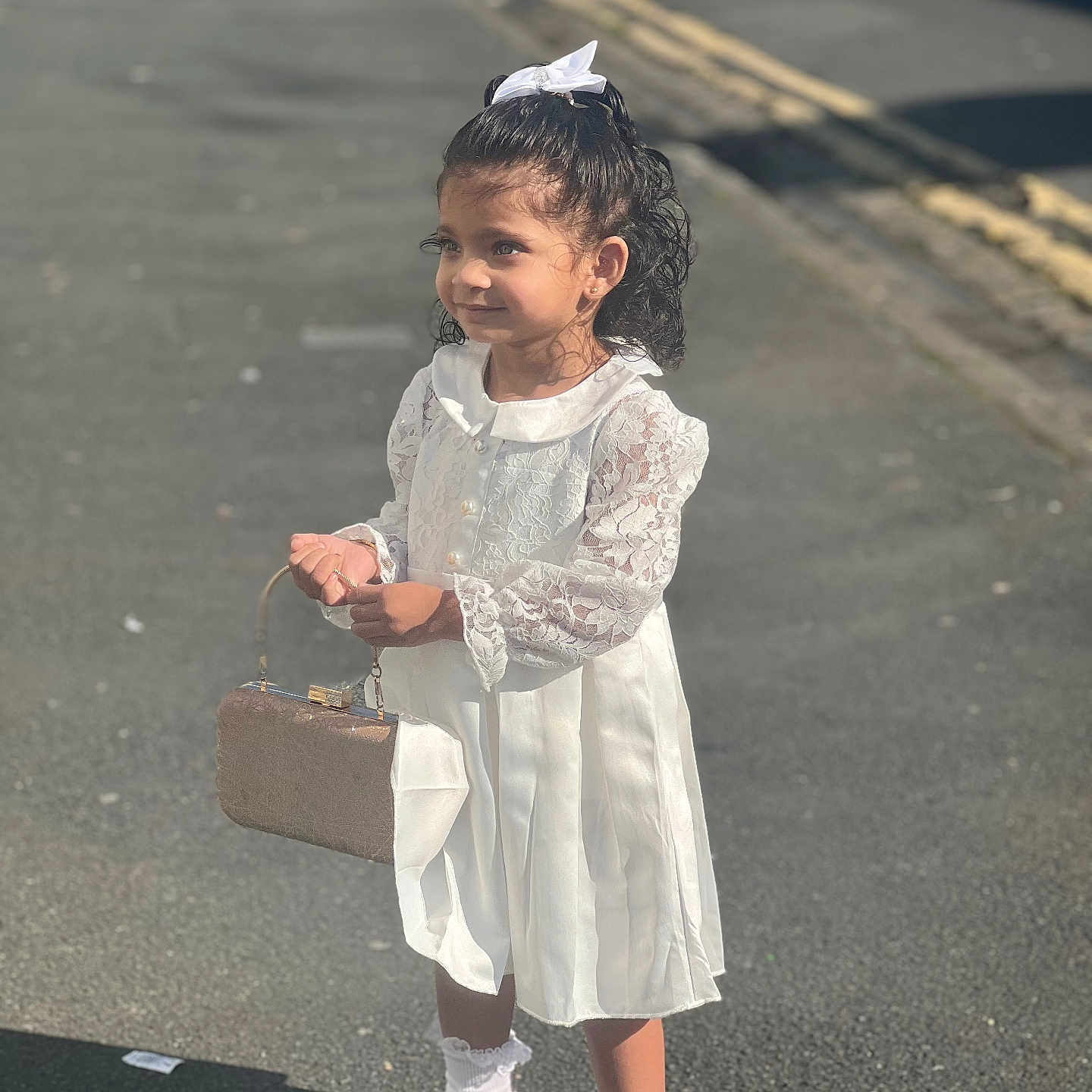 Daleyza is registered to the contest to win money with this photo: accessories, child, curly_hair, cute, fashion, girl, innocence, outdoor, pavement, purse, shadow, shoes, side_view, smile, socks, street, sunlight, white_bow, white_dress, young_child