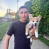 Bernabé a rejoint le concours — aidez-le/la à gagner de superbes lots ! man, person, dog, corgi, puppy, pet, animal, outdoor, portrait, selfie, smiling, happy, tongue, ears, harness, holding, park, path, trees, stadium