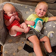 Junior is registered to the contest to win money with this photo: baby, toddler, child, couch, blanket, clothing, smile, face, footwear, sitting, indoor, fabric, pattern, toy, hand, leg, furniture, happy, casual, home
