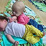baby, infant, child, floor, blanket, clothing, play, cuddle, jeans, pink_shirt, yellow_pants, feet, wooden_floor, toddler, cute, indoor, person, two_children, lying_down, happy
