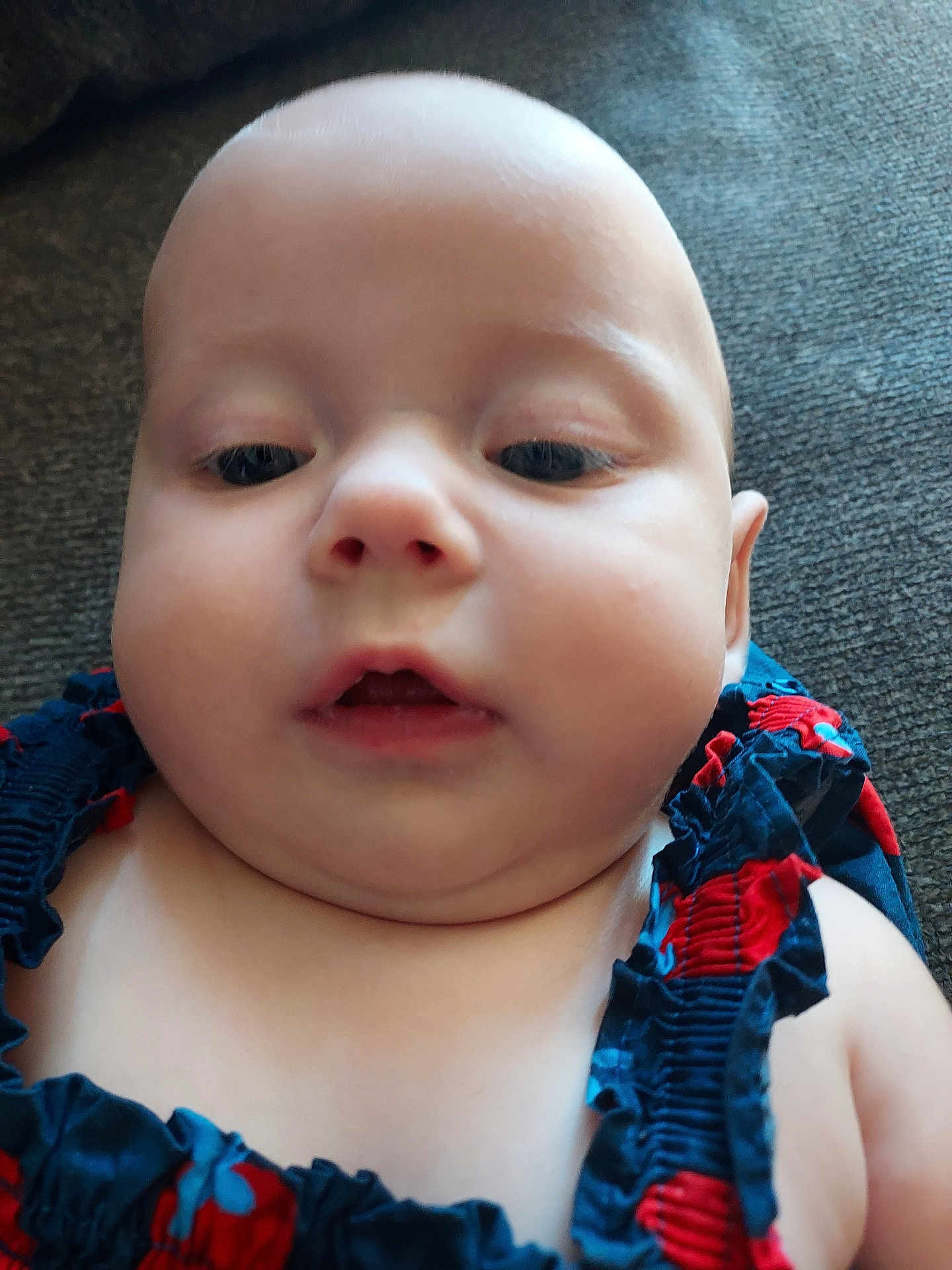 Maja joined the competition — help win amazing prizes! baby, face, child, closeup, person, skin, infant, portrait, clothing, couch, texture, indoors, cute, expression, chubby_cheeks, blue, red, ruffles, young, head