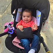 Ayla is registered to the contest to win money with this photo: baby, black, blanket, child, clothing, face, footwear, handbag, happy, jeans, outdoor, person, pink, sidewalk, smile, socks, stroller, sunlight, toy, wristlet