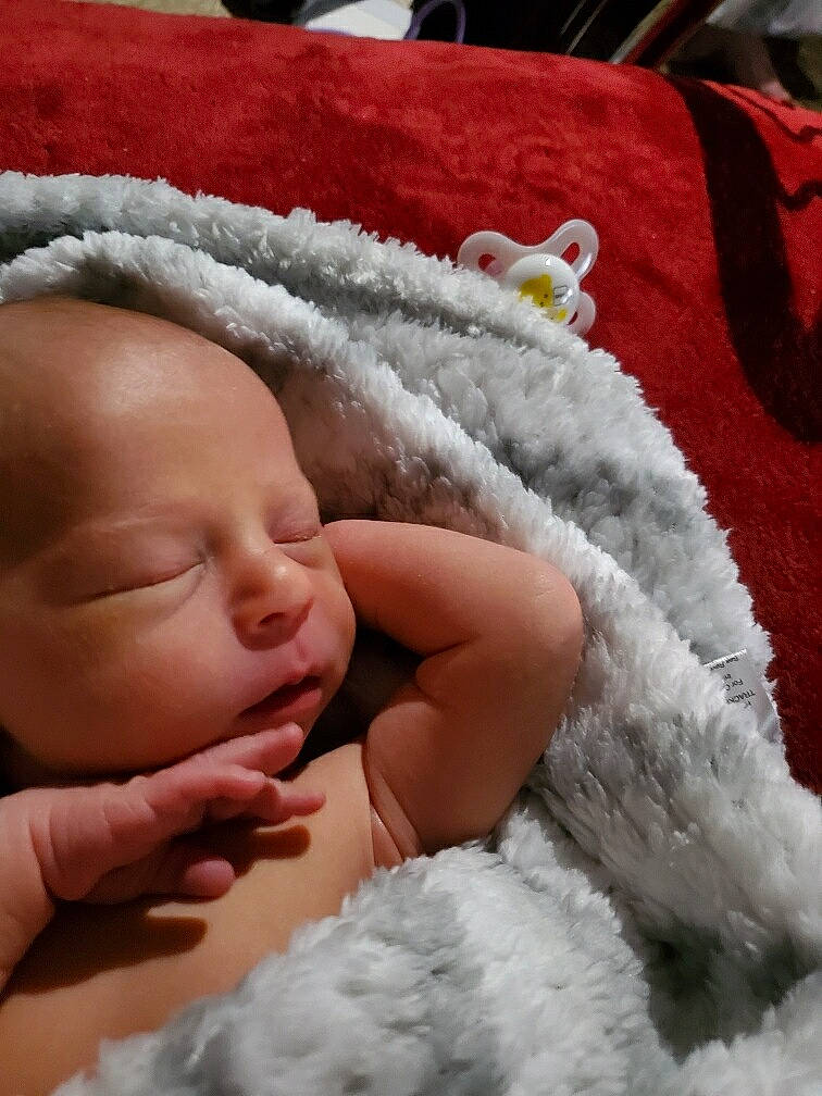 Eric is registered to the contest to win money with this photo: baby, baby_sleeping, baby_toddler_clothing, cheek, child, close_up, comfort, fashion_accessory, finger, fur, happy, linens, nose, person, red, skin, sleeve, textile, thumb, toddler