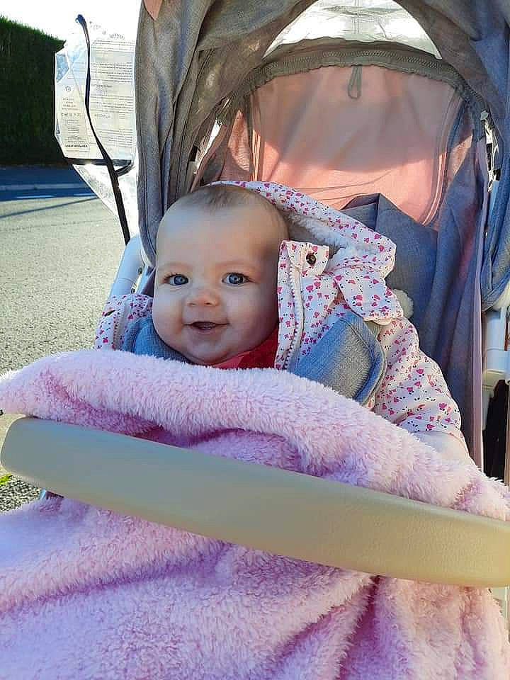 Mia participe au concours pour gagner de l'argent avec cette photo : baby, baby_carriage, baby_safety, baby_toddler_clothing, cheek, comfort, eye, fun, hairstyle, happy, head, iris, person, pink, product, purple, skin, smile, toddler, vertebrate