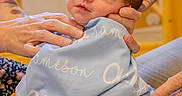Ollie joined the competition — help win amazing prizes! baby, infant, blanket, sneaker, hands, person, blue, indoor, cute, child, footwear, closeup, holding, newborn, soft, portrait, cozy, skin, head, face