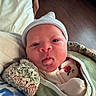 Sterling joined the competition — help win amazing prizes! newborn, baby, infant, face, portrait, lying_down, bundled, blanket, knit_blanket, beanie, hat, onesie, clothing, bed, cozy, indoors, home, wooden_floor, tongue, closeup