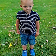 Ylan a rejoint le concours — aidez-le/la à gagner de superbes lots ! child, boy, grass, greenery, leaves, outdoor, casual_clothing, shorts, polo_shirt, blue_shoes, nature, daylight, standing, curious_expression, summer, young, portrait, footwear, park, casual