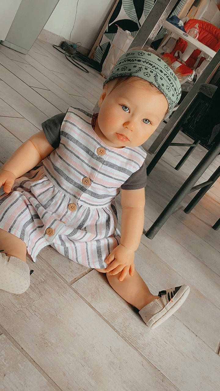 Wendy participe au concours pour gagner de l'argent avec cette photo : baby_toddler_clothing, cap, comfort, elbow, floor, flooring, foot, hardwood, headwear, human_leg, joint, knee, leg, pattern, person, sitting, sleeve, sock, thigh, toddler