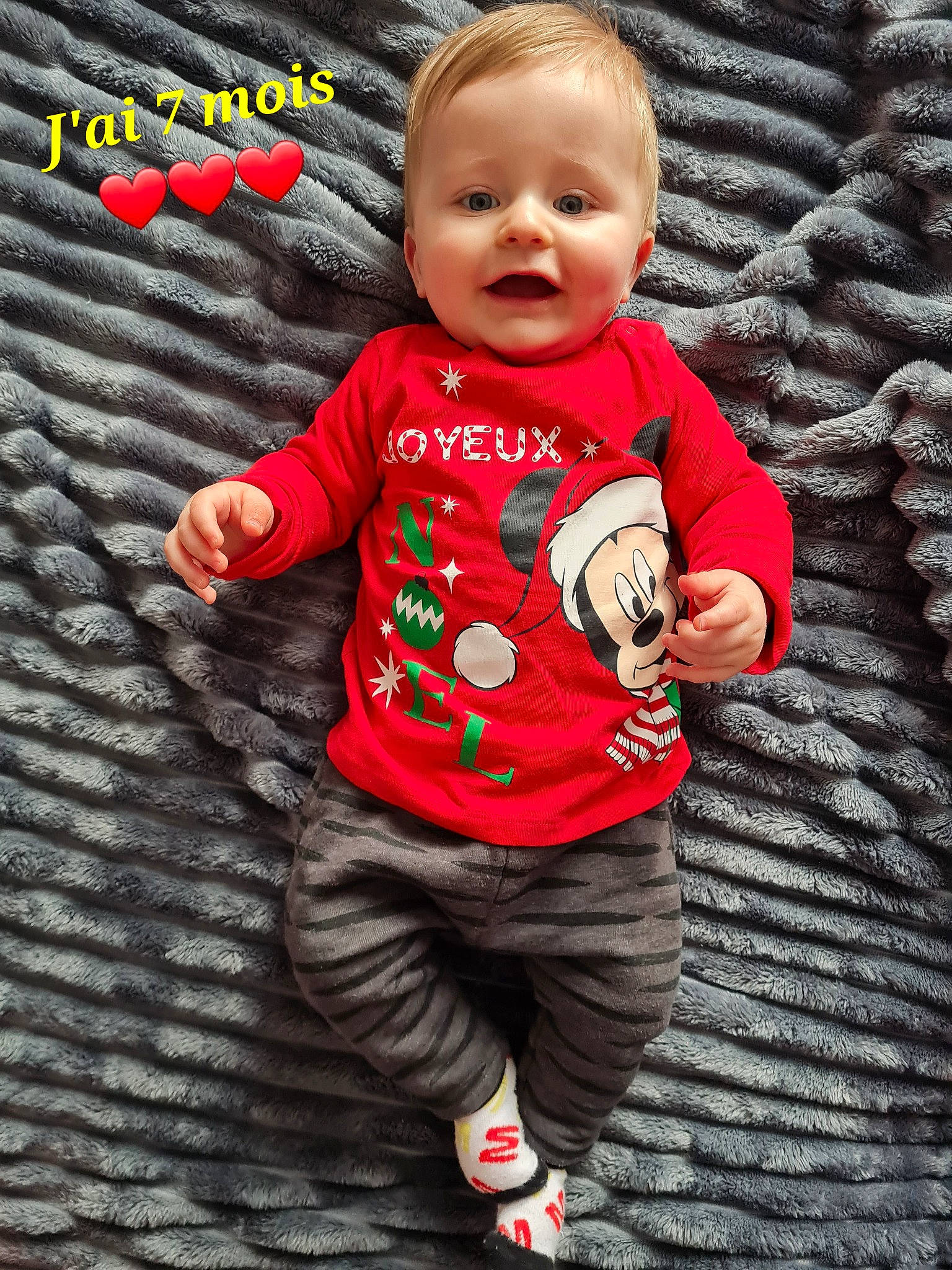 Timéo a rejoint le concours — aidez-le/la à gagner de superbes lots ! arm, baby, baby_toddler_clothing, black, cheek, eye, face, facial_expression, gesture, grey, happy, outerwear, person, pink, skin, sleeve, smile, standing, t_shirt, textile