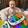 Raelyn joined the competition — help win amazing prizes! baby, infant, play_mat, toy, musical_keyboard, colorful, smiling, happy, wooden_chair, plush_toy, floor, indoors, cute, child, playing, person, clothing, expression, home, flooring