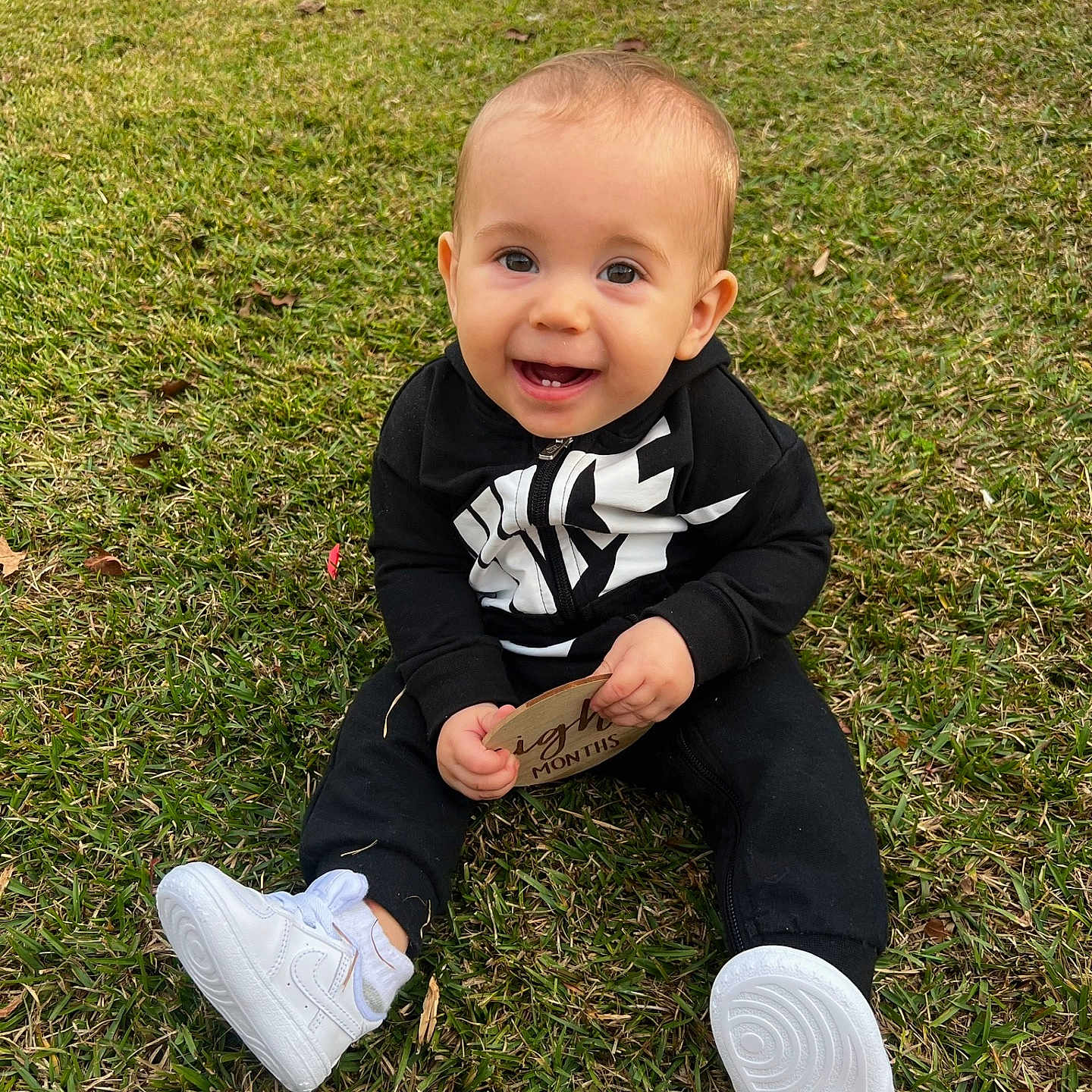 Malikai is registered to the contest to win money with this photo: baby, clothing, face, footwear, grass, head, jeans, lawn, nature, outdoors, pants, park, person, photography, plant, portrait, shoe, sitting, sneaker, text