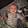 baby, infant, smile, striped_clothing, onesie, blanket, plaid_blanket, soft_texture, happy, face, head, cute, lying_down, indoors, child, person, expression, cozy, warm, gesture