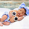 Ariyah is registered to the contest to win money with this photo: newborn, baby, sleeping, blue_bow, headband, flower_sunglasses, blanket, wooden_background, infant, cute, resting, soft_texture, peaceful, small_hands, small_feet, lying_down, indoors, portrait, child, adorable