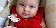 Aïcha participe au concours pour gagner de l'argent avec cette photo : baby, blanket, child, closeup, comfort, cushion, cute, expression, face, hand, indoors, infant, pacifier, portrait, red_clothing, resting, seat, skin, soft_texture, young