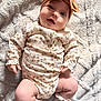 baby, infant, child, smiling, headband, bow, onesie, floral_pattern, blanket, soft_texture, cute, chubby_legs, socks, indoors, portrait, happy, lying_down, closeup, skin, adorable
