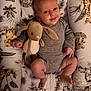 baby, smiling, plush_toy, bunny, onesie, blanket, animal_print, toddler, infant, cute, soft_toy, lying_down, cozy, indoors, portrait, child, happy, cuddly, young_child, nursery